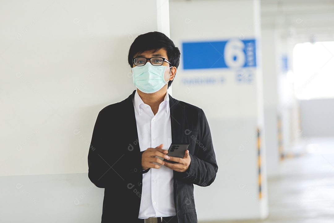 Homem asiático de máscara e usando celular