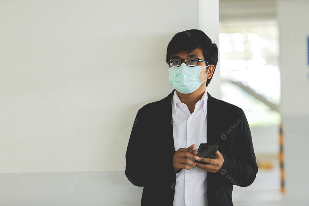 Homem asiático de máscara e usando celular