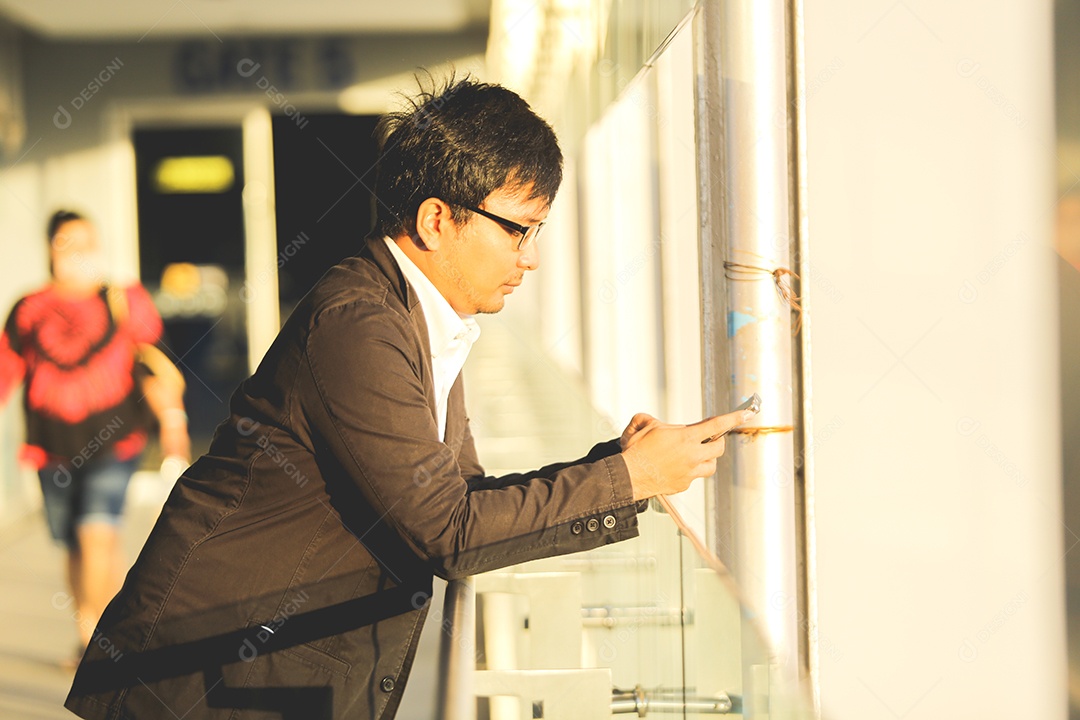 Homem asiático usando celular parado no corredor