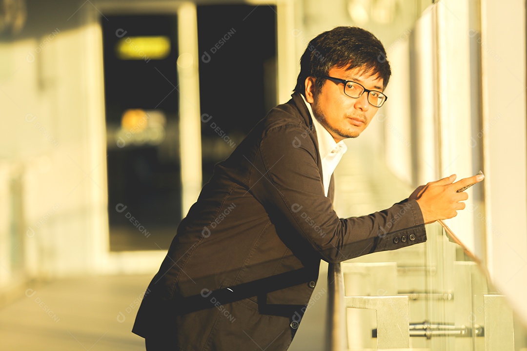 Homem asiático usando celular parado no corredor