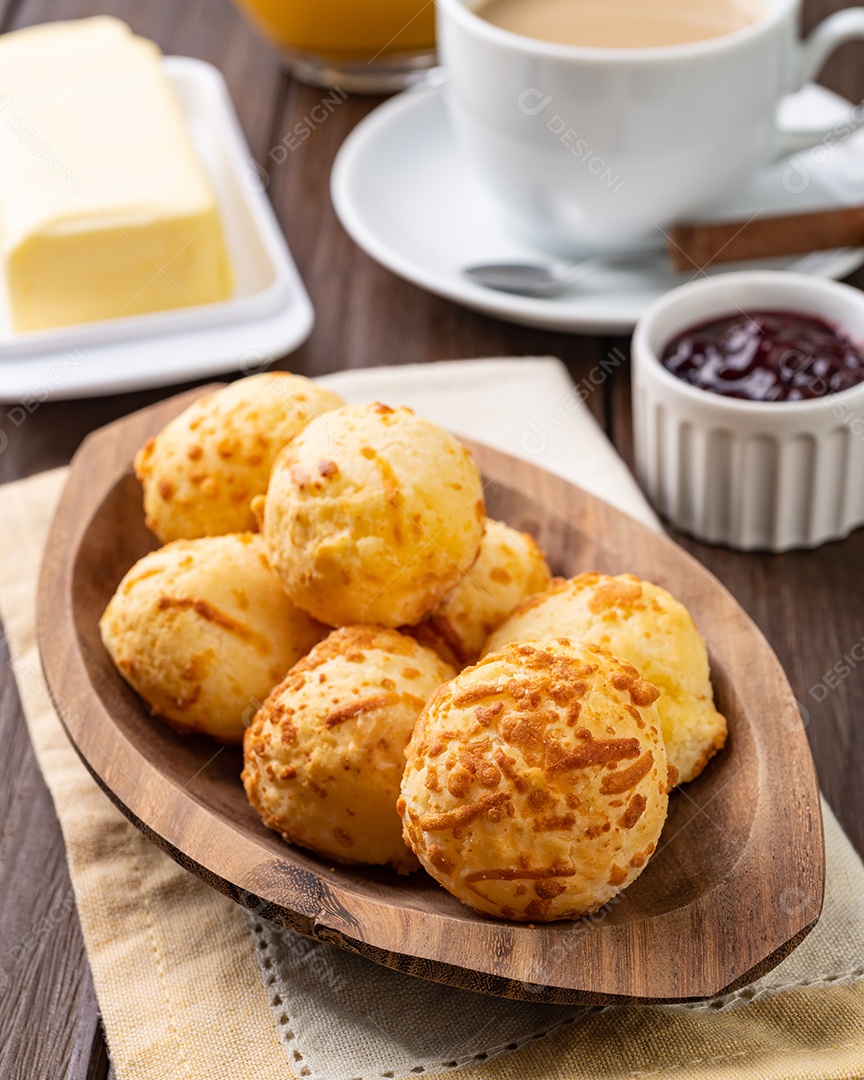 Pão de queijo típico brasileiro em um prato sobre a mesa de madeira.