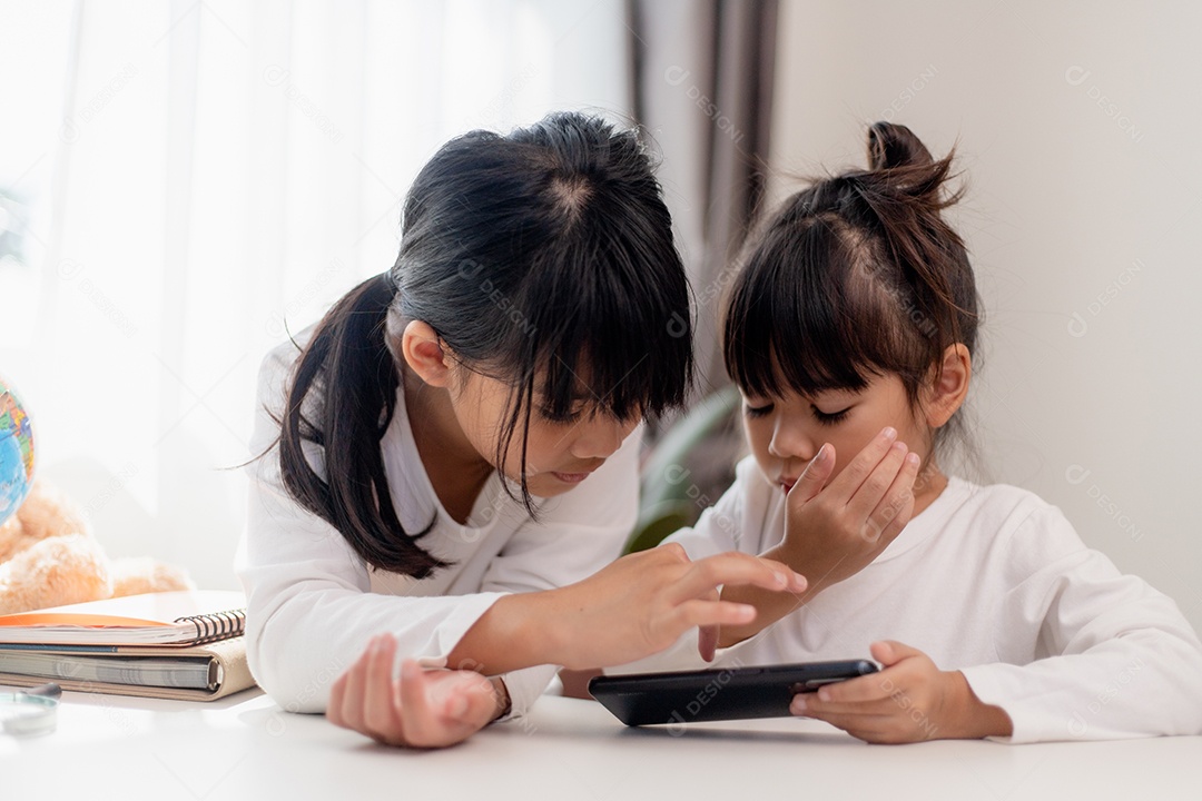 Crianças de conceito e gadgets. Duas irmãs irmãs olham para o telefone e sorriem