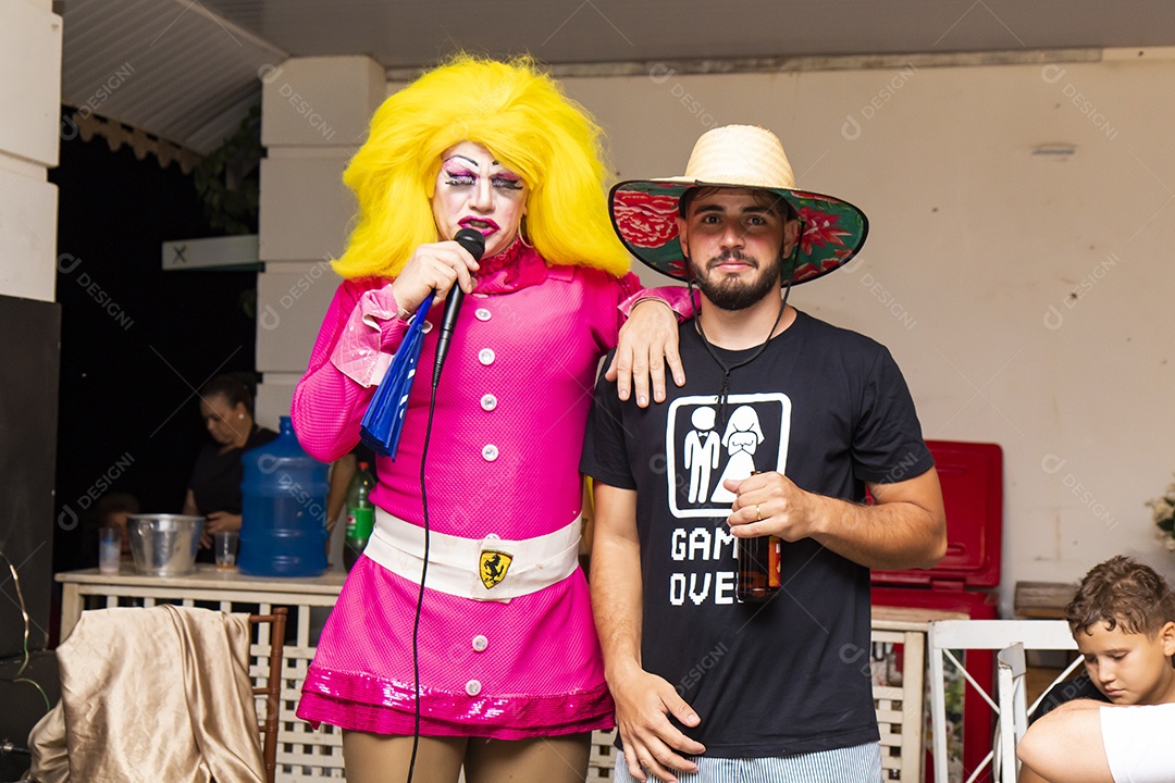 Homem usando chapéu de palha ao lado de uma pessoa fantasiada