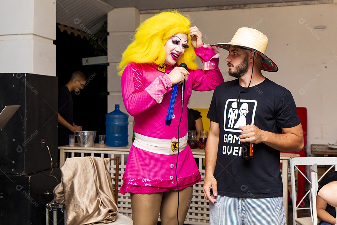 Homem usando chapéu de palha ao lado de uma pessoa fantasiada
