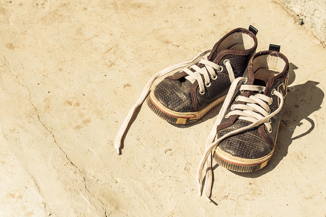 Sapatos de lona velhos de criança em frente a uma casa rura