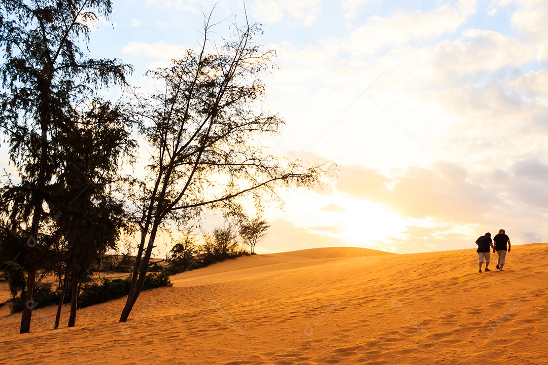 Gêmeos asiáticos caminham na duna de areia de Mui Ne ao pôr do sol