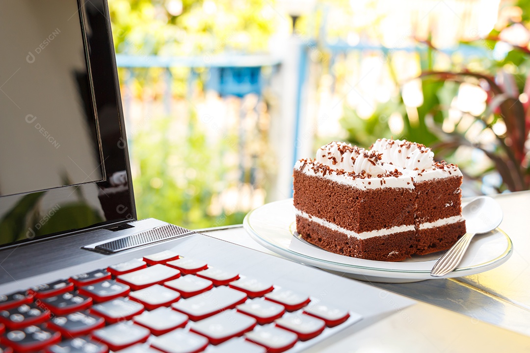 Bolos de chocolate com creme branco por cima e notebook em casa