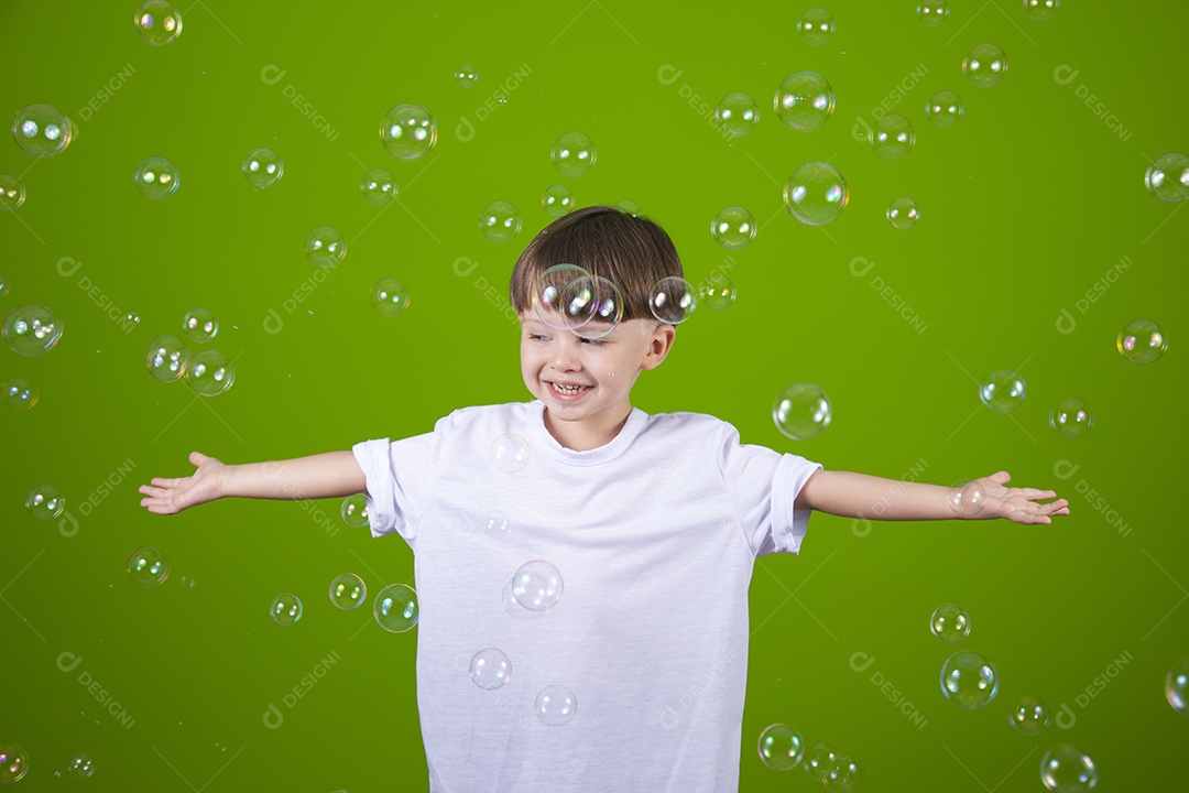 Lindo garotinho feliz e sorridente usando camiseta branca sobre fundo isolado verde