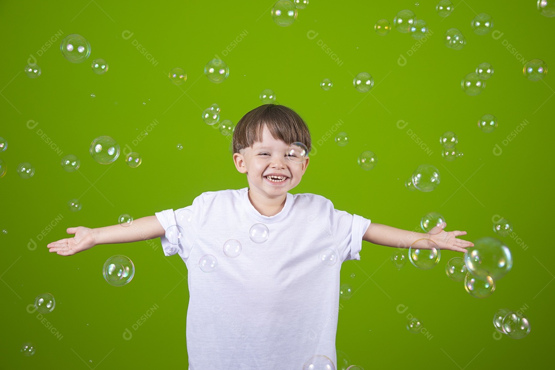 Lindo garotinho feliz e sorridente usando camiseta branca sobre fundo isolado verde