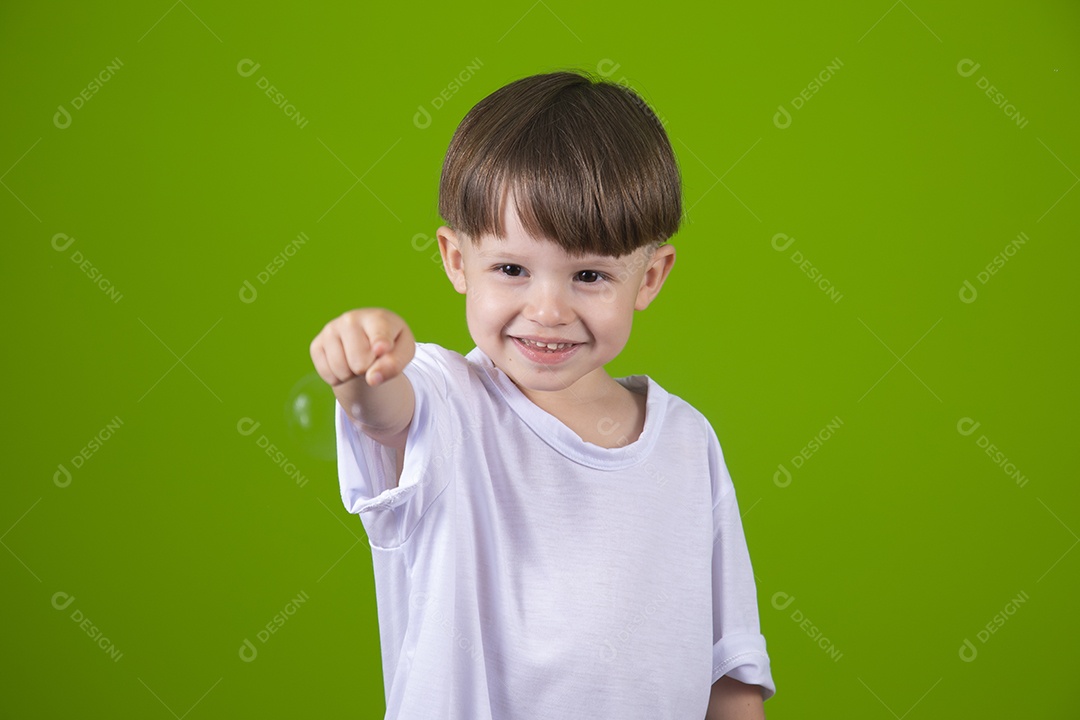 Lindo garotinho feliz e sorridente usando camiseta branca sobre fundo isolado verde