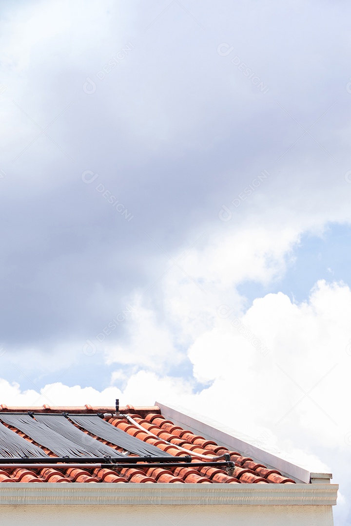 Sistema de aquecimento de água no telhado da casa em um dia ensolarado e nublado.