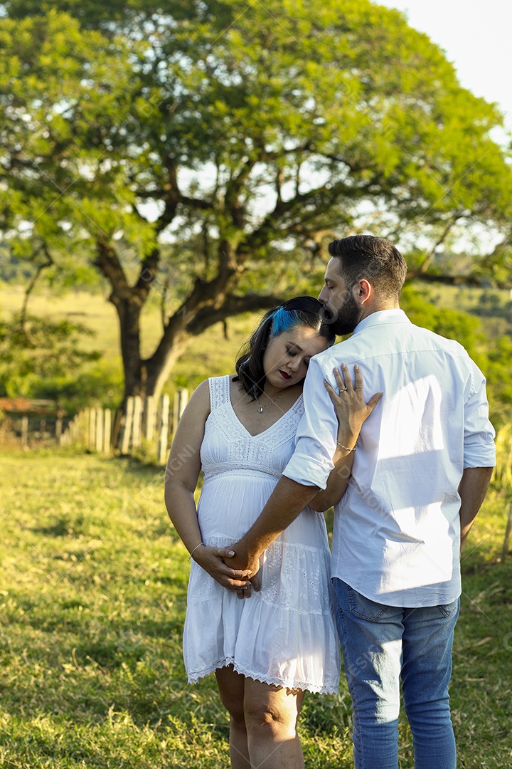Homem com ao lado de sua esposa gravida sobre um lindo lugar paisagem