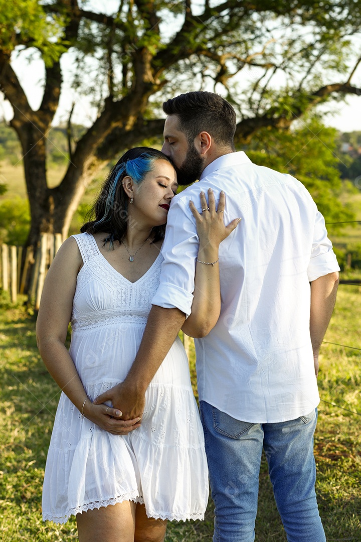 Homem com ao lado de sua esposa gravida sobre um lindo lugar paisagem
