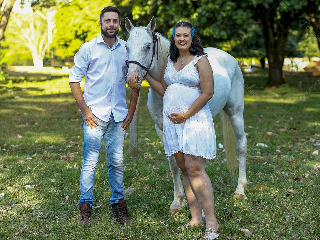 Homem com ao lado de sua esposa gravida ao lado de cavalo sobre uma fazenda