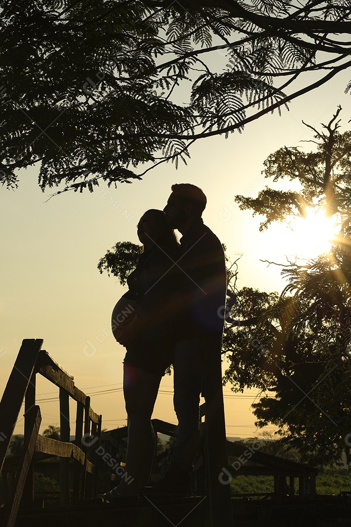 Homem com ao lado de sua esposa gravida sobre um lindo lugar paisagem