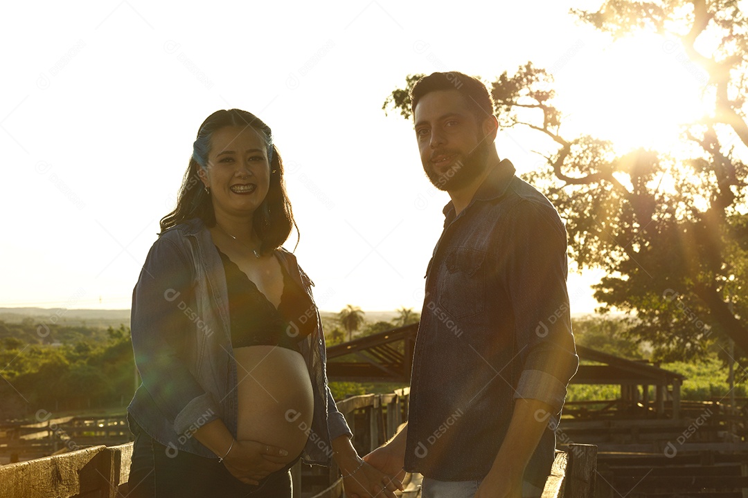 Homem com ao lado de sua esposa gravida sobre um lindo lugar paisagem