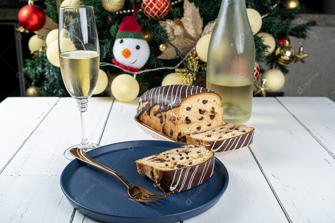 Fatia de chocotone cercada por vidro e garrafa de espumante