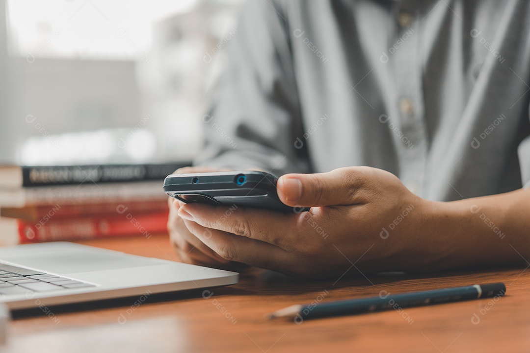 Homem com celular e laptop no escritório
