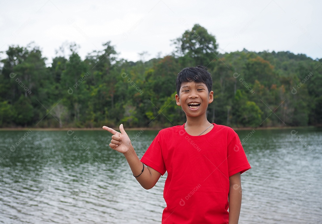 Menino feliz sorridente na beira do rio