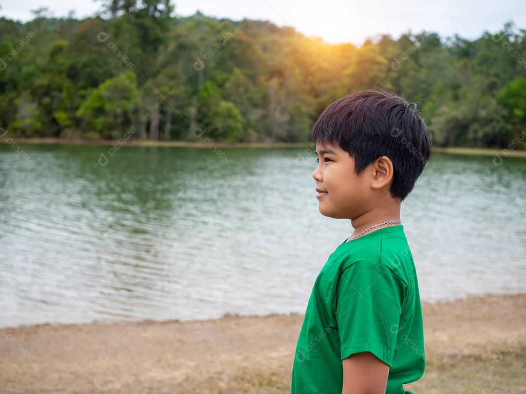 Menino feliz sorridente na beira do rio