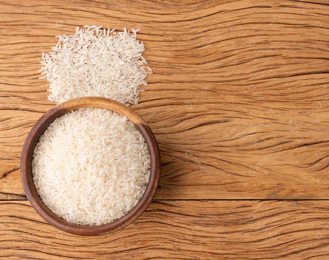 Arroz branco cru em uma tigela sobre a mesa de madeira com espaço de cópia.