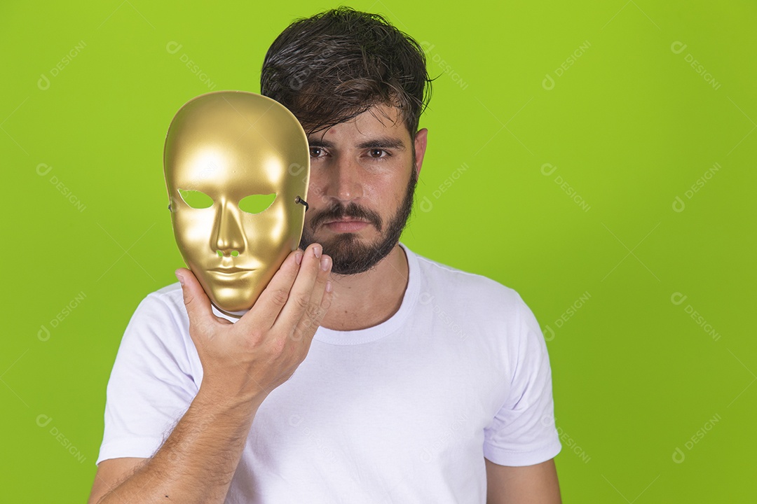 Homem jovem garoto barbudo segurando máscara dourada sobre fundo isolado