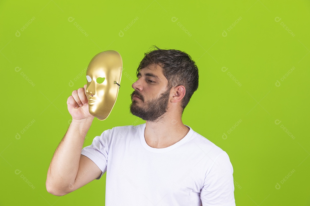 Homem jovem garoto barbudo segurando máscara dourada sobre fundo isolado