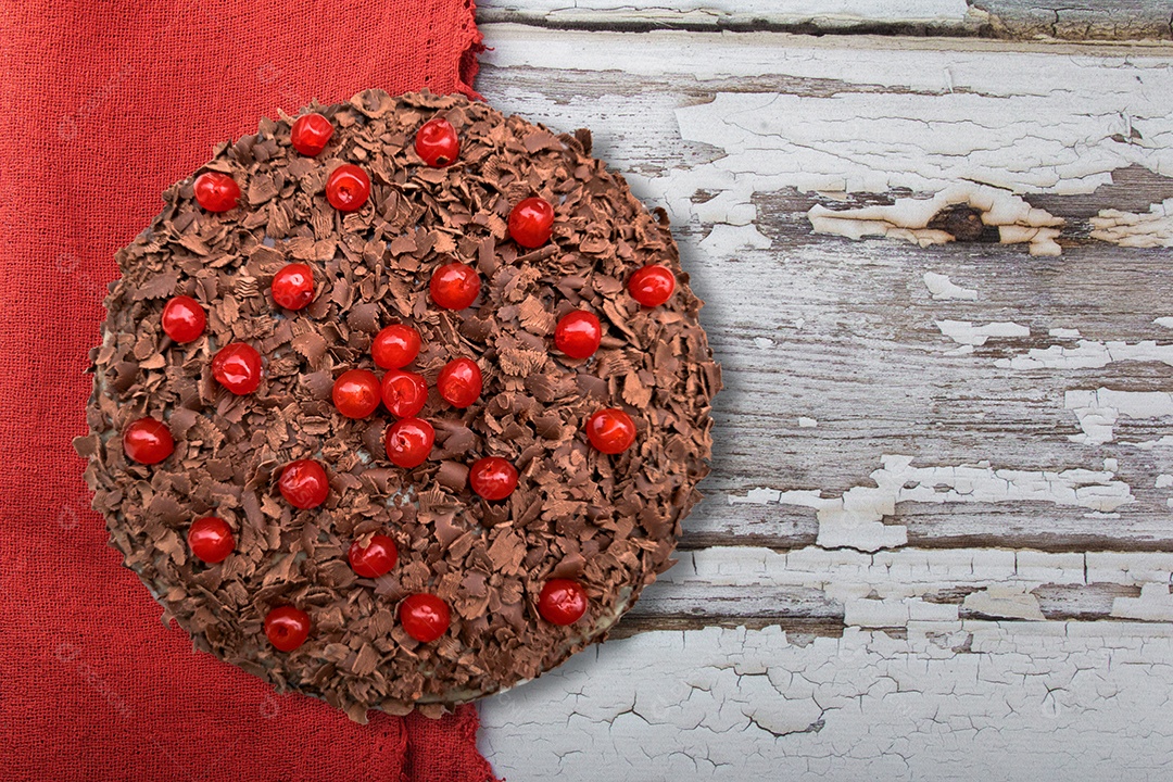 Bolo de chocolate com cerejas em fundo de madeira.