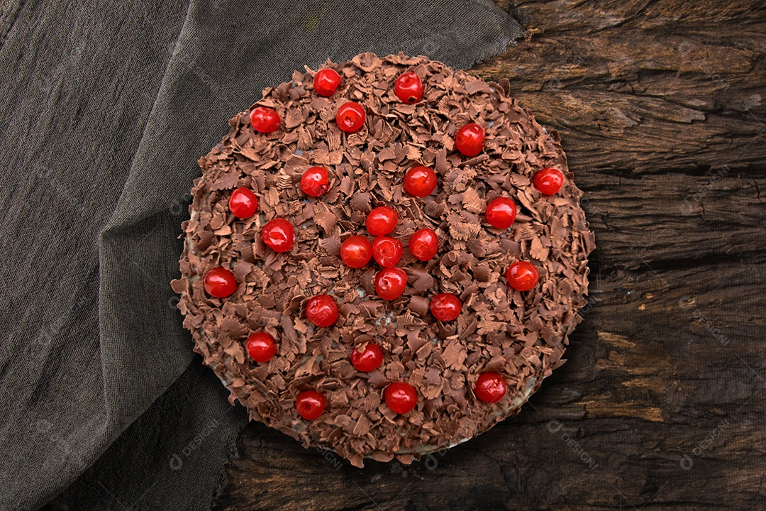 Bolo de chocolate com cerejas em fundo de madeira.