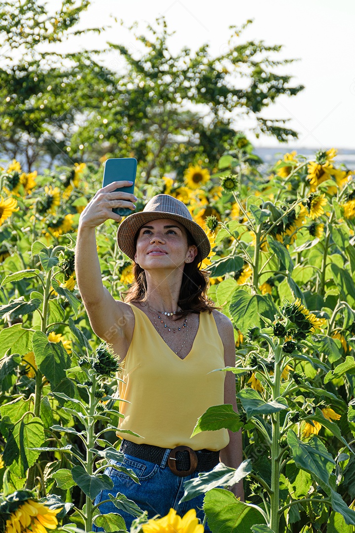 Mulher brasileira com chapéu tirando uma foto de si mesma com seu smatphone