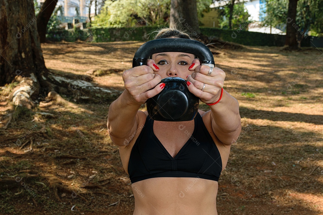 Detalhe de ombros de treinamento brasileiro de 42 anos com kettlebell ao ar livre