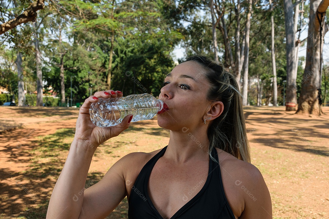 Brazilian woman, 42 years old, well-built, drinking water in a public square