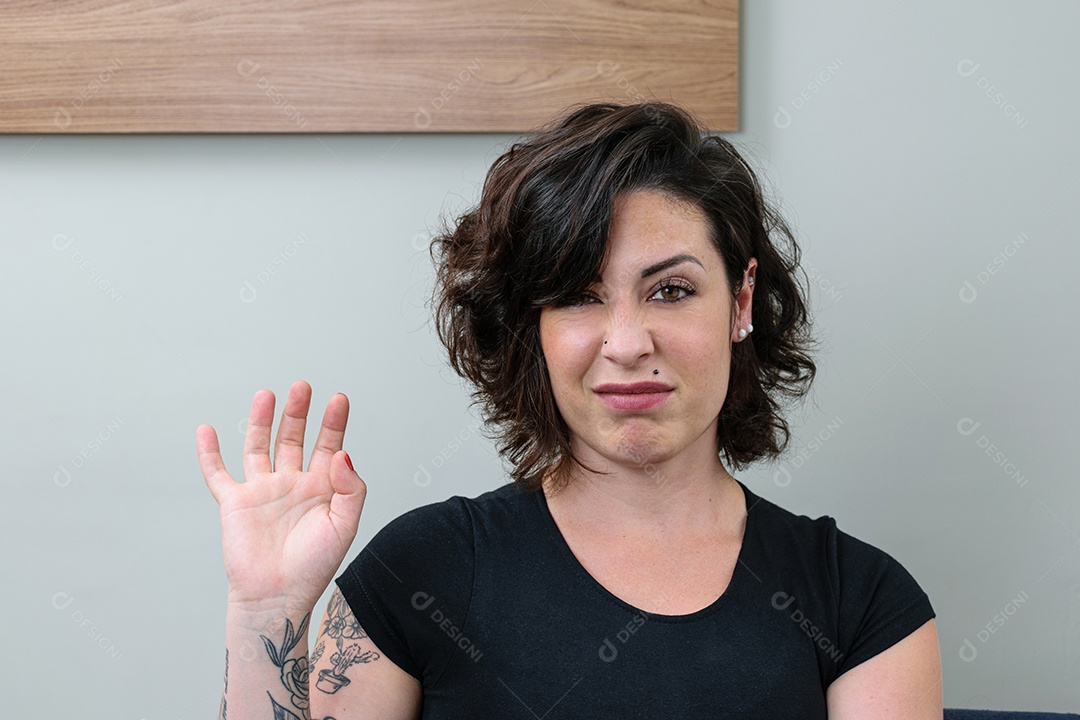 Mulher brasileira, tatuada, com mão e rosto mostrando desprezo