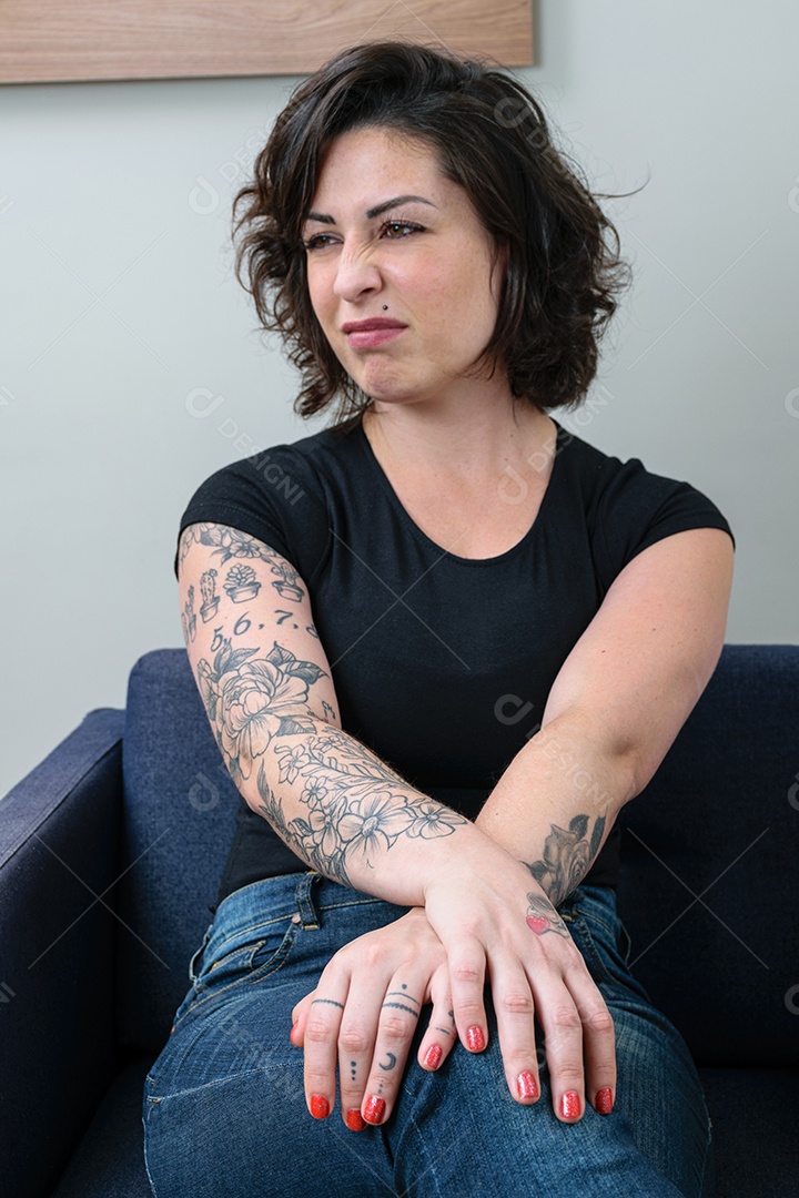 Mulher brasileira, tatuada, com as mãos cruzadas e olhando para o lado, demonstrando desprezo
