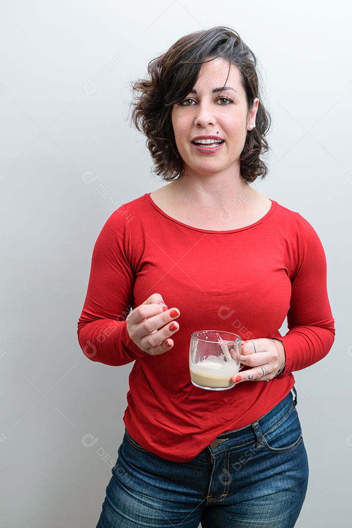 Mulher brasileira, de boca aberta, segurando uma caneca de cappuccino