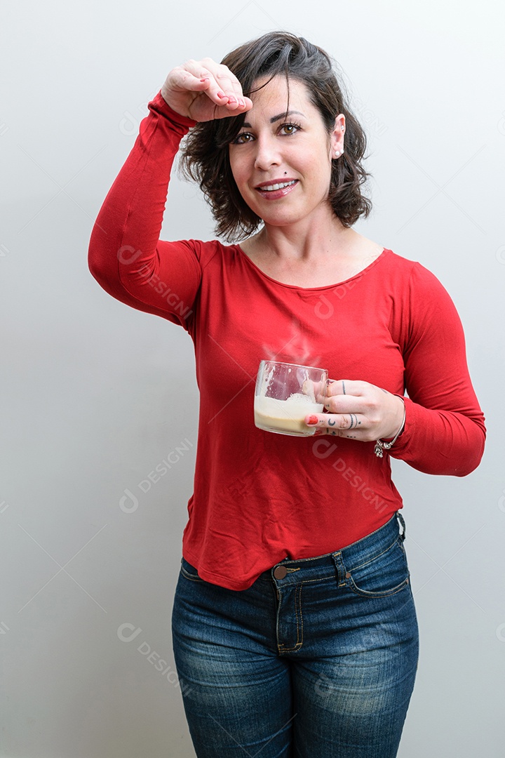 Brasileira, segurando uma caneca de cappuccino, uma mão na testa