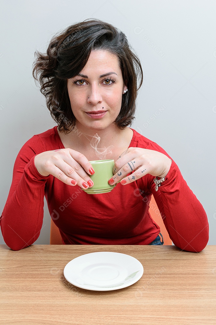 Mulher brasileira, de semblante sério, com uma xícara de café