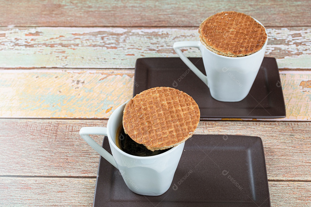 Dois biscoitos stroopwafel com xícaras de café.