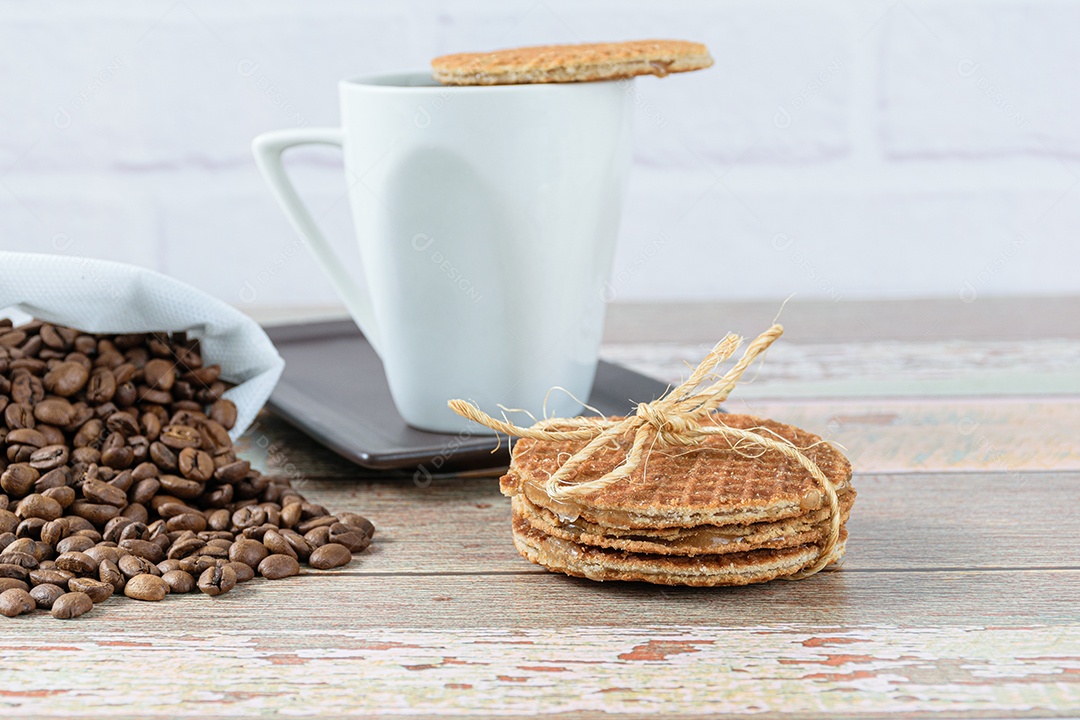 Biscoitos Stroopwafel com laço de sisal ao lado de uma xícara de café