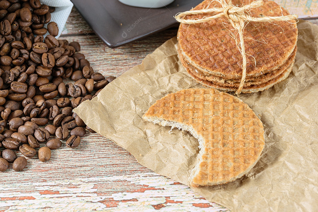 Detalhe de biscoitos stroopwafel com uma mordida ao lado de grãos de café
