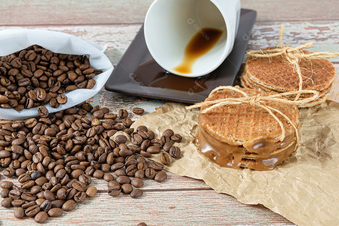 closeup de stroopwafels empilhados em papel pardo, ao lado de uma xícara de
