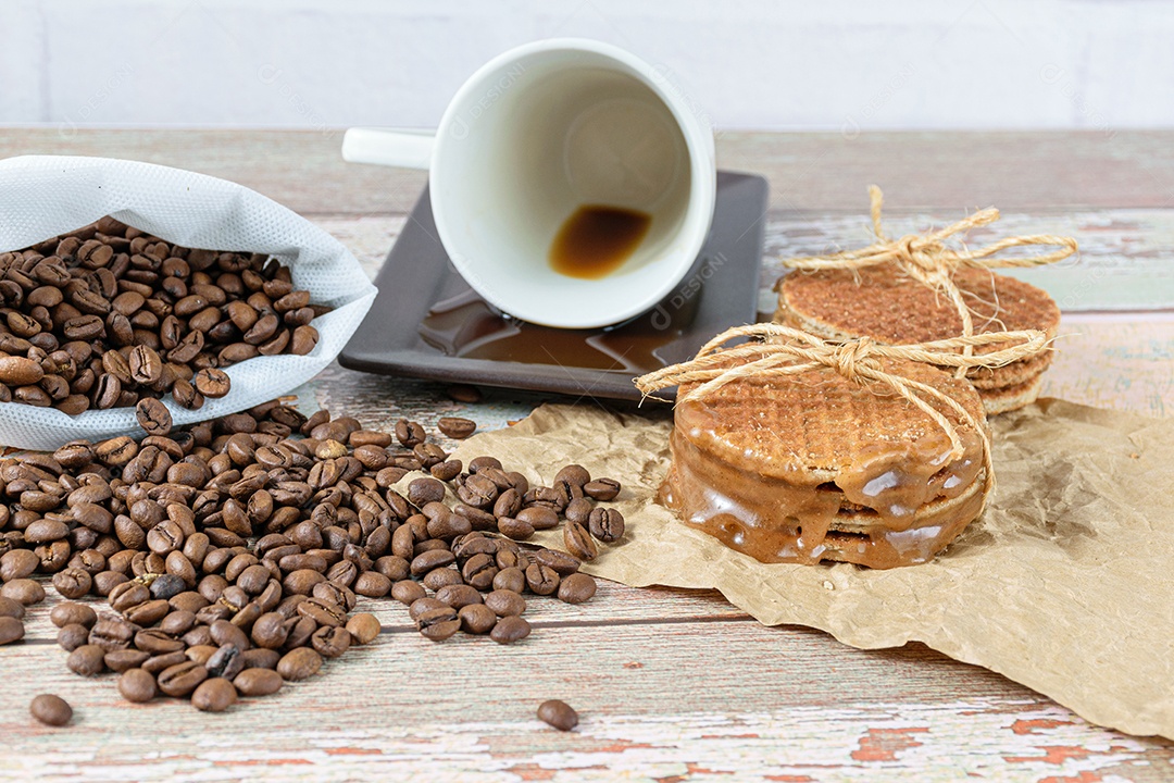closeup de stroopwafels empilhados em papel pardo, ao lado de uma xícara de café