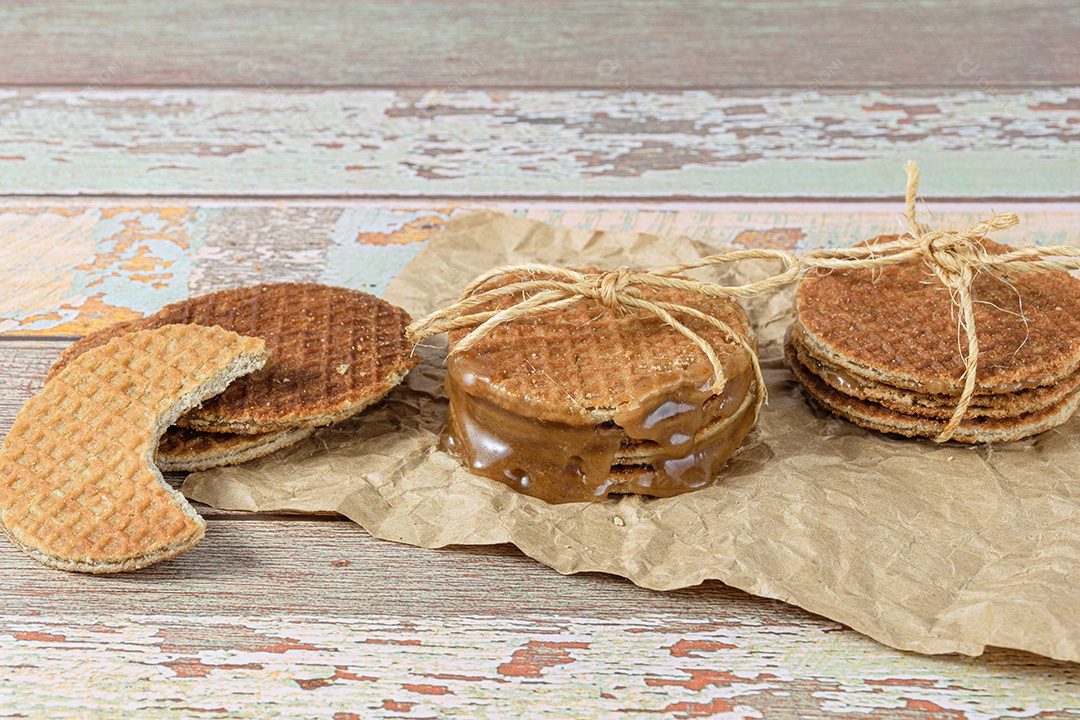 Empilhe stroopwafels em papel pardo, ao lado de outro biscoito com uma mordida