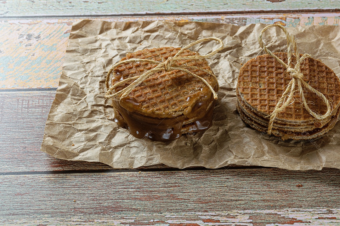 Close de uma pilha de stroopwafel em papel pardo com xarope de glicose derretido.