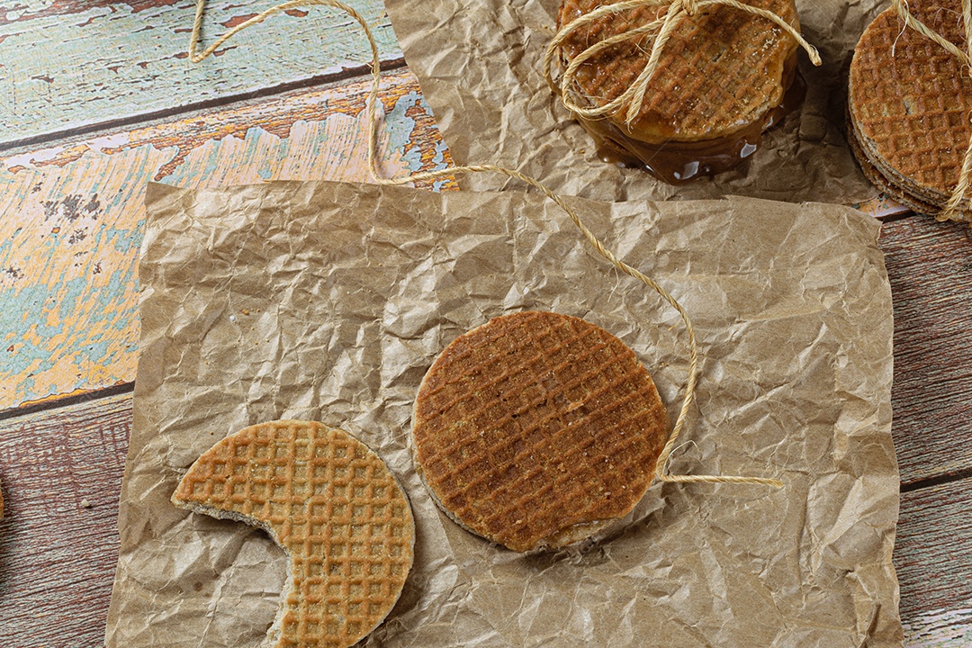 Stroopwafel com uma mordida em papel pardo ao lado de outro biscoito