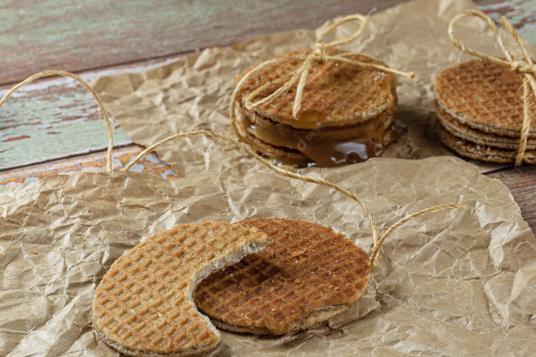 Stroopwafel com uma mordida em papel pardo ao lado de outro biscoito