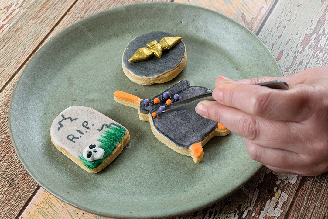 Biscoito amanteigado sendo decorado pelo padeiro com bolas de açúcar.