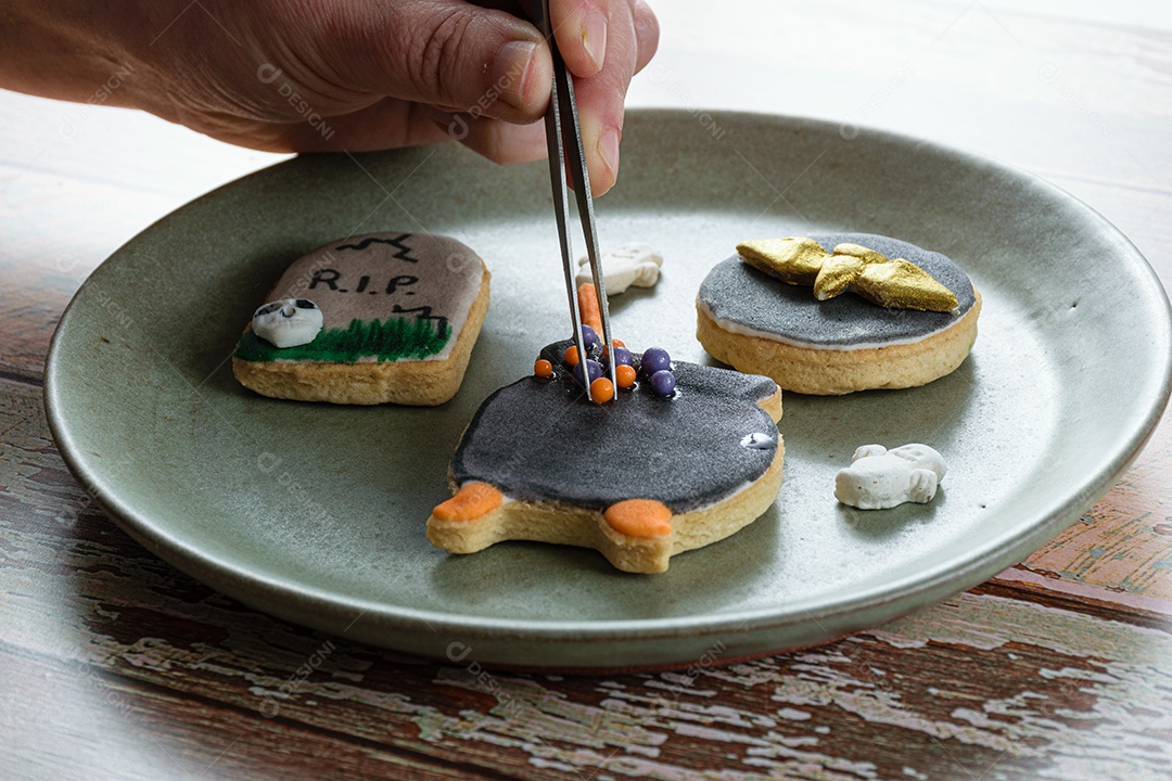 Biscoito amanteigado sendo decorado pelo padeiro com bolas de açúcar.