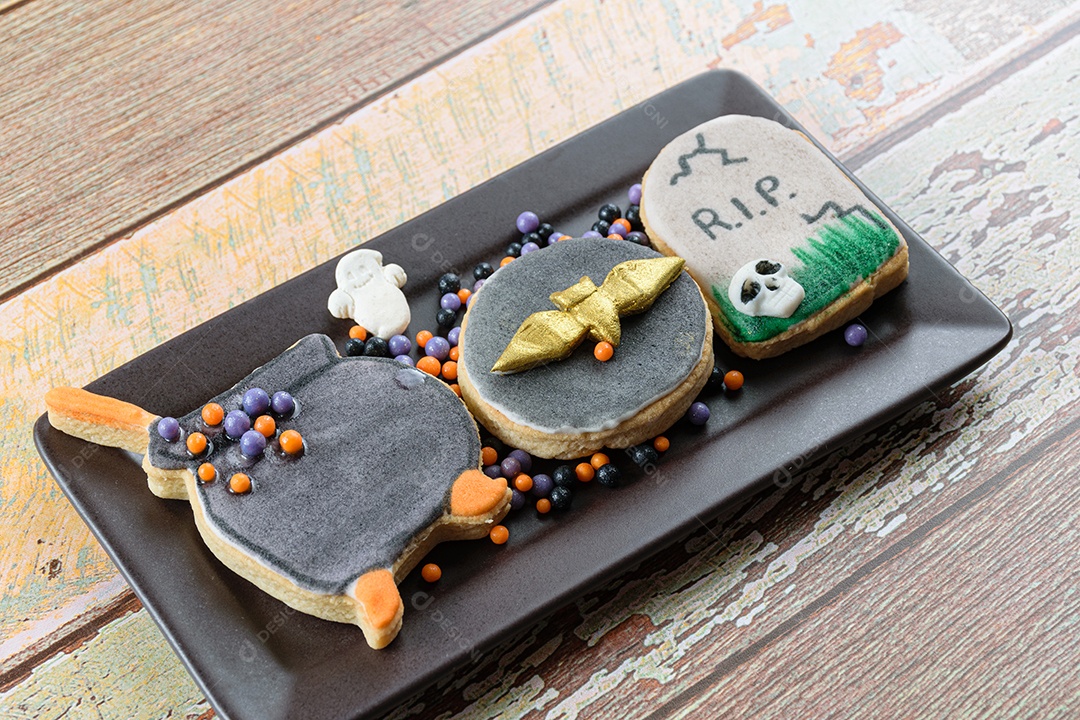 Biscoitos amanteigados temáticos de Halloween ao lado de pequenas bolas de açúcar