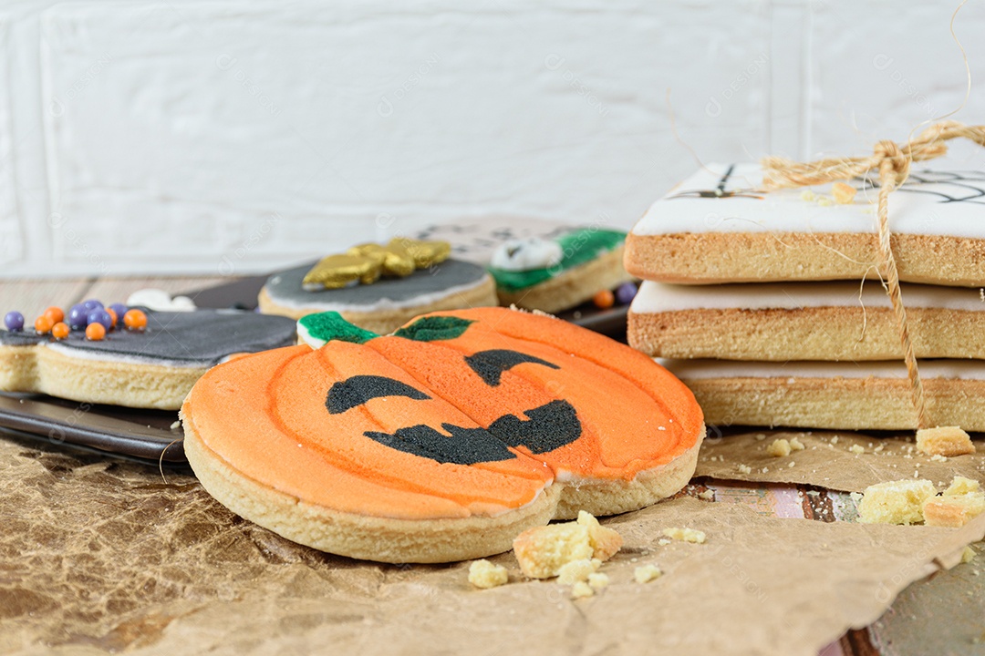 Close-up de biscoitos amanteigados em um papel pardo. No centro um biscoito em forma de abóbora